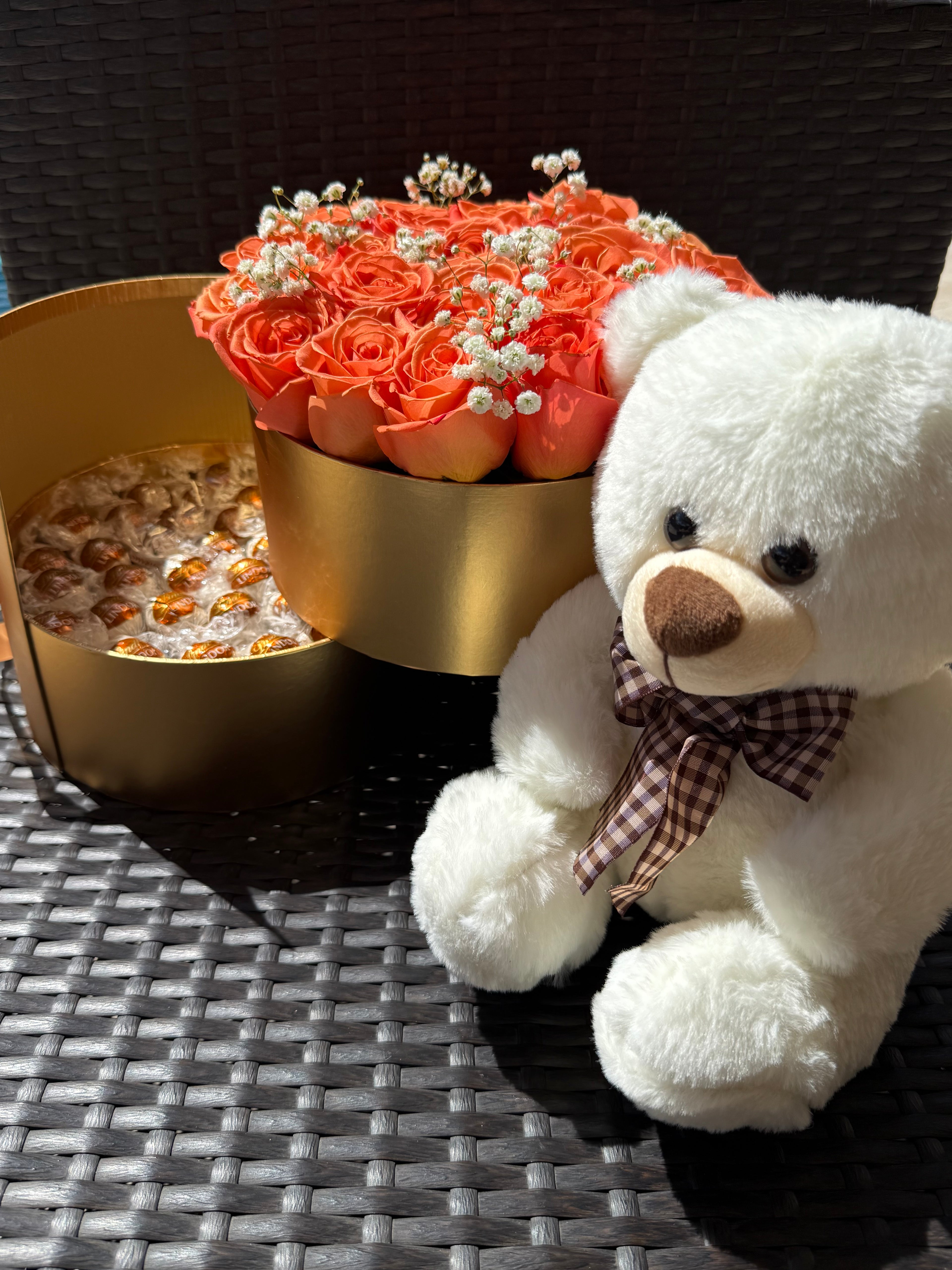 White teddy bear with a bouquet of flowers on a textured surface - Lovy Details Miami