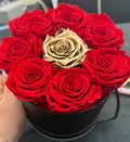 Box of red roses preserved  with a central gold rose on a dark surface - Lovy Details Miami