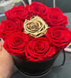 Box of red roses preserved  with a central gold rose on a dark surface - Lovy Details Miami