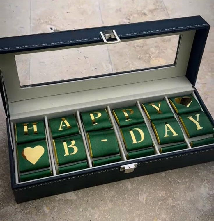 Watches box with green and gold 'Happy Birthday' jewelry pieces on a stone surface - Lovy Details Miami